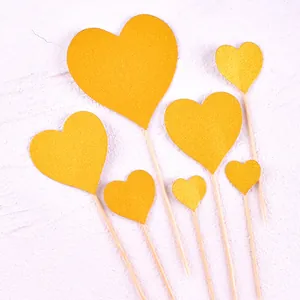 Vue détaillée de sept cake toppers en forme de cœur pailleté doré pour décoration de desserts