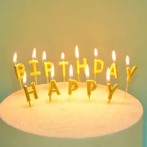 Nahaufnahme von brennenden goldenen Happy Birthday Buchstabenkerzen auf der Torte
