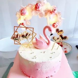 Detailed view of glowing floral arch and pink swan cake topper decorations