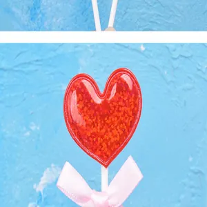 Primer plano de un adorno para tarta de corazón rojo con purpurina y un lazo rosa