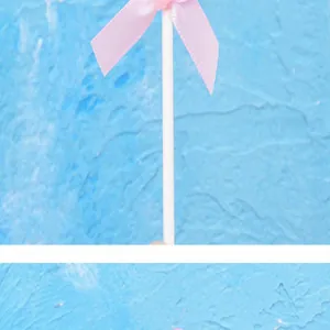 Primer plano de un palito para tarta con un delicado lazo de cinta rosa
