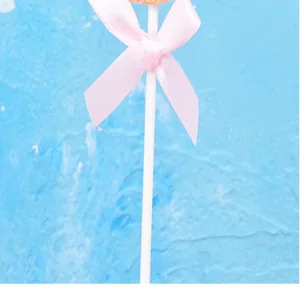 Detalle de un lazo de cinta rosa en un palito para pasteles sobre fondo azul