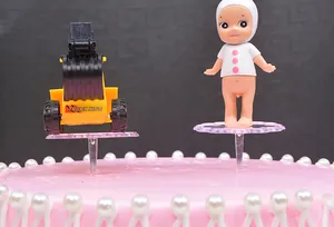 Close-up of transparent plastic cake topper base for doll figurines on pink pearl cake