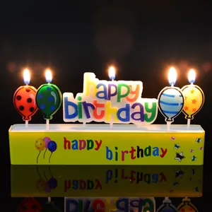 Colorful 'Happy Birthday' letter candles with creative balloon shapes on a yellow base