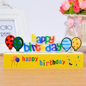 Colorful Happy Birthday letter candles with balloon shapes on a festive yellow base.
