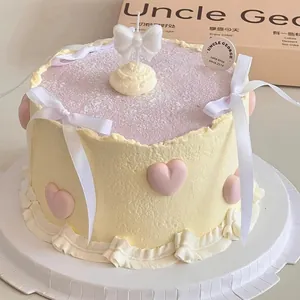Close-up detail of a pearlescent white bow-knot candle topper on a cream-decorated cake