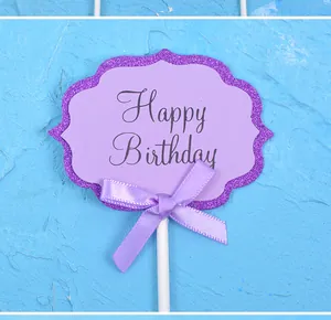 Detailed view of a purple glitter Happy Birthday cake topper with a purple satin bow