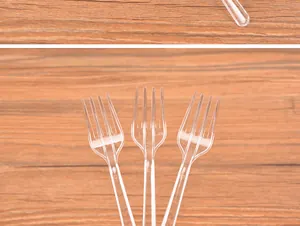 Close-up detail of three disposable transparent plastic four-tine forks on wood