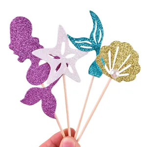Close-up of glittery mermaid theme cake toppers with starfish fish tail and shell designs