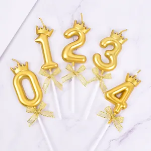 Detailed view of golden number candles 0-4 with crowns and glittery bows for cakes