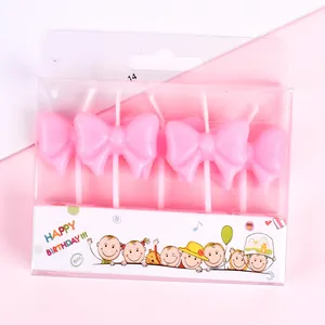 Close-up of four pink bow-shaped birthday candles in festive gift box packaging