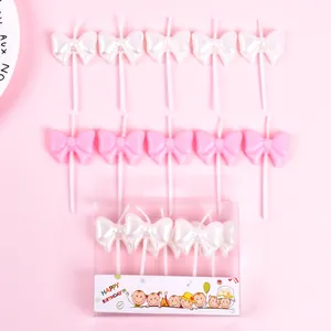 Set of white and pink bow birthday candles for cake decoration in clear box packaging