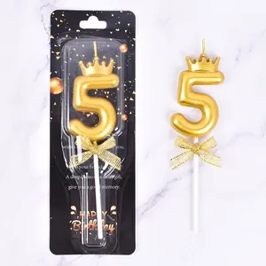 Detail of gold number 5 birthday candle with crown and bow in its packaging
