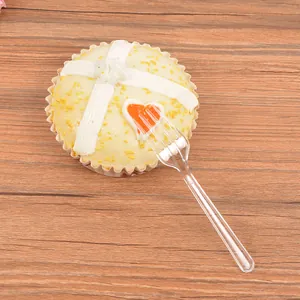 Disposable clear plastic 4-tine dessert fork presented on a cupcake with wood background