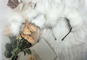 Detailed shot of white furry animal ear headbands on a soft white faux fur rug.