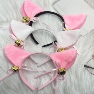 Close-up of pink and white plush cat ear headbands with golden bells and pink ribbons.