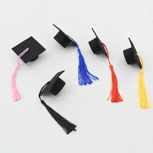 Close-up of mini black graduation caps with colorful tassels in pink blue and red
