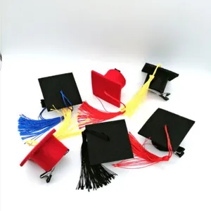 Macro view of mini graduation cap hair clips in red and black with colorful tassels