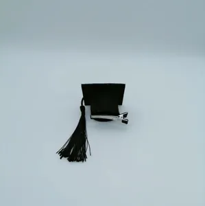 Close-up detail of a miniature black graduation cap hair clip with tassel