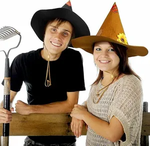 Una pareja feliz con sombreros de espantapájaros puntiagudos y un rastrillo de Halloween
