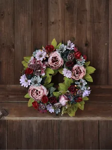 A close-up detailed view of an artificial pink peony wreath on a rustic wooden door.