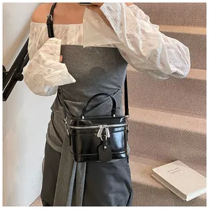 Sac boîte noir brillant élégant avec ferrures argentées porté en bandoulière dans un escalier