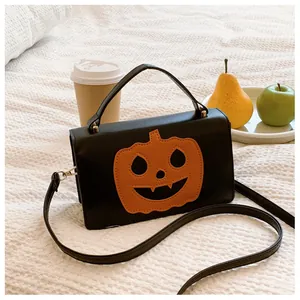 Cozy lifestyle detail of a black Halloween pumpkin crossbody bag on white bedding