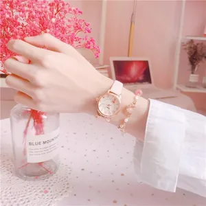 Detail view of a stylish pink student wrist watch and gold star bracelet on a wrist