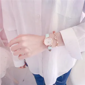 Detailed shot of a girl wearing a cute mint green cat-ear watch and a gold charm bracelet