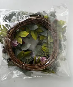 Vintage artificial pink peony floral wreath with green leaves in protective plastic packaging