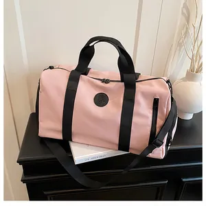 Detail view of a stylish pink travel duffel bag with black straps and circular logo.