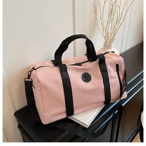 Side view of pink large capacity travel gym bag with black straps on a black sideboard