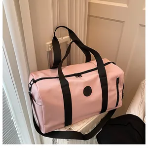 Detail view of pink travel duffel bag with black straps mounted on a suitcase