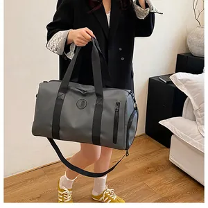 Model holding a grey large capacity travel duffel bag in a modern indoor setting.