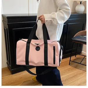 Detailed lifestyle view of a large pink gym duffle bag with black straps being handheld