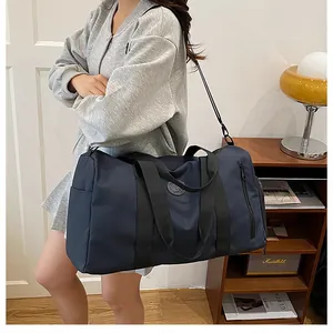 Detailed view of a large navy blue travel bag with dry-wet separation carried by a model