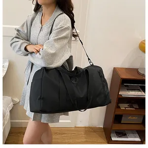 Side view of a woman carrying a large black fitness duffel bag over her shoulder