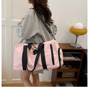 Large capacity pink gym and travel bag with black shoulder strap worn by a model