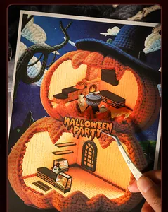 Close-up of Halloween pumpkin house stickers being applied with tweezers for scrapbooking.