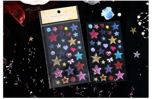 Primo piano di adesivi in resina glitterata a forma di stella e cuore per diario.