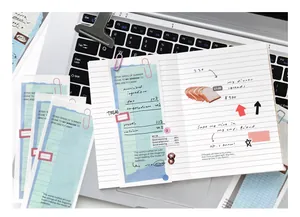 Nahaufnahme von blauen Gitter-Notizzetteln und Notizbuch auf einer Laptoptastatur.
