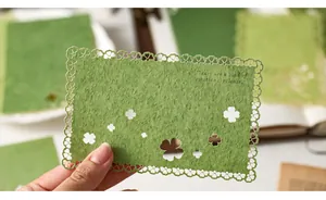 Detail of green textured paper with hollow clover patterns and delicate scalloped lace edges.