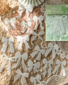 Dettaglio ravvicinato di vari adesivi a fiocco in pizzo PET bianco sparsi su carta vintage marrone.