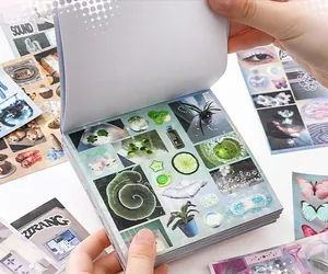 Close-up of a thick scrapbooking sticker book with various aesthetic dream-themed designs.