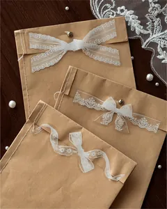 Dettaglio di eleganti adesivi in pizzo PET bianco su buste in carta kraft vintage