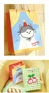 Close-up detail of medium vertical gift bags featuring cute cat and cherry illustrations