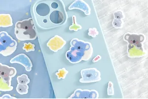 Vue détaillée d'autocollants en feutrine mignons koalas sur une coque de téléphone bleue