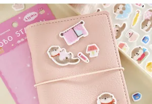 Gros plan d'autocollants en feutre de loutre sur un carnet rose pour décoration