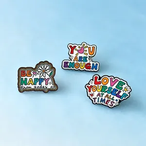 Detailed macro view of three colorful enamel pins featuring motivational English quotes.