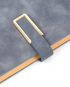 Close-up of the golden rectangular buckle and gray PU leather texture on a notebook cover.